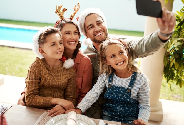 Altijd klaar voor een kerst-selfie Bijgesneden opname van een gezin van vier personen die samen een selfie maken op eerste kerstdag