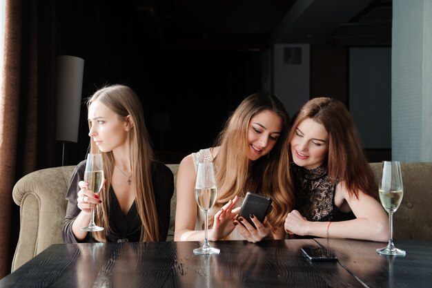 Altijd verbonden, internetverslaving, jonge meisjes in café die naar hun smartphones kijken, sociaal netwerkconcept.