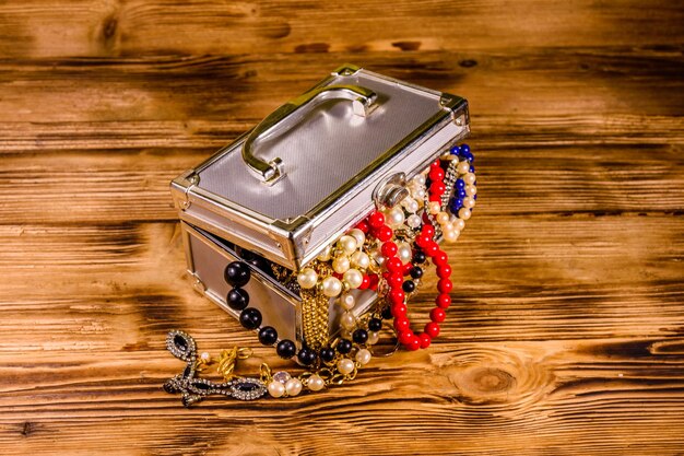 Aluminium case full of different jewelry on wooden table