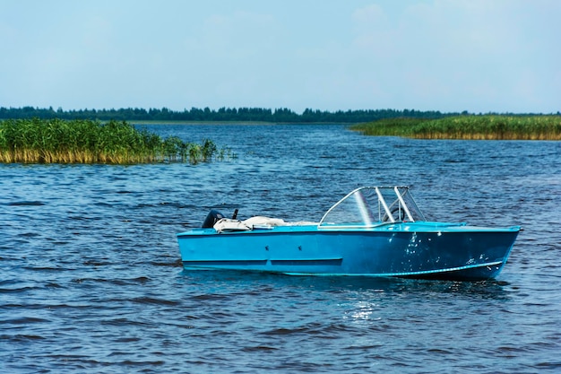 Aluminum blue fishing boat with a motor near the lake shore fishing active recreation