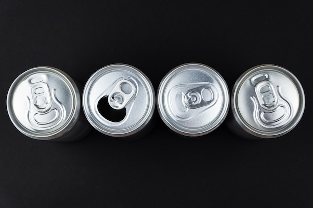 Aluminum cans are displayed in a row on a black desk