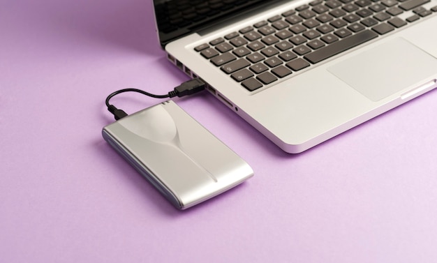 Aluminum external hard drive partial laptop view purple surface