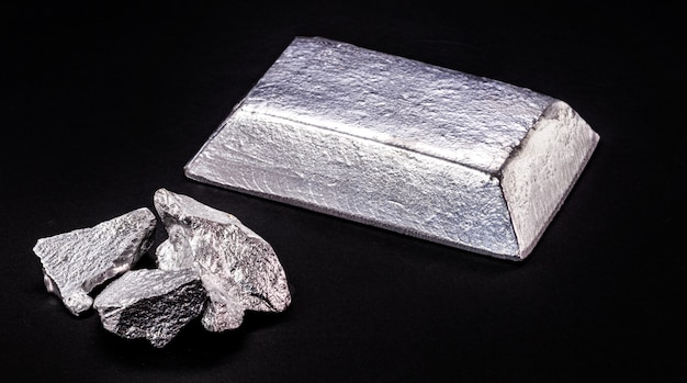 Aluminum ingot or bar next to aluminum ore, recycling or metal\
industry concept