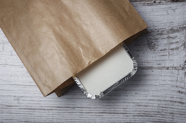 Aluminum take away food containers prepared for delivery in recyclable paper bags