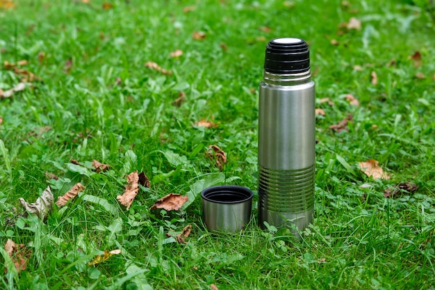 Steel Thermos With A Cup Of Hot Tee Standing On Old Stump In