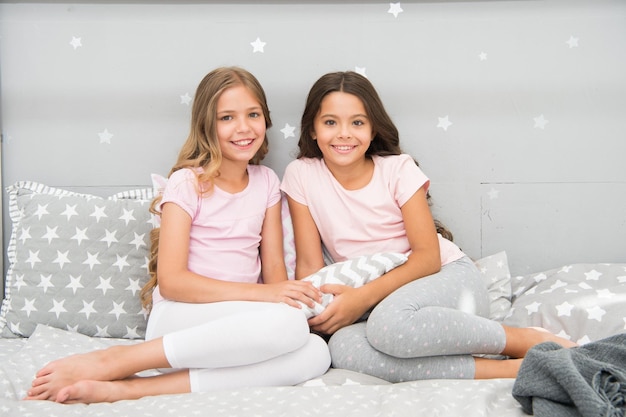 Always cute. Happy girls sit on bed. Beauty look of little girls. Small girls wear home clothing. International day of girl child. Beautiful us.