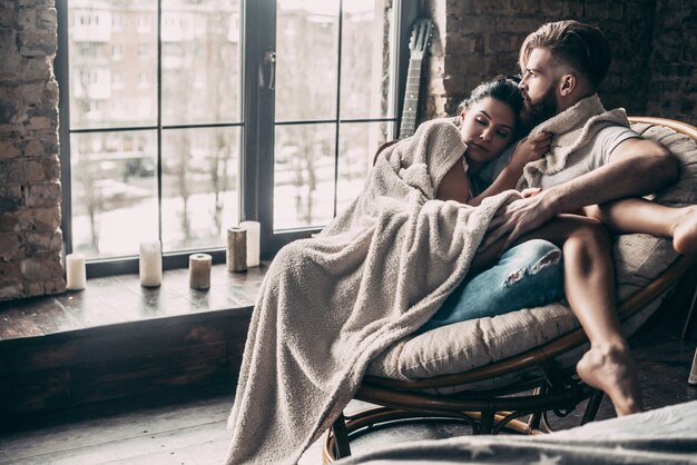 Photo always protecting her. beautiful young couple covered with blanket resting together