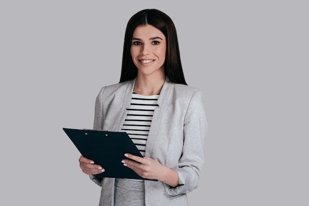 Always ready to work.  Businesswoman posing against the wall