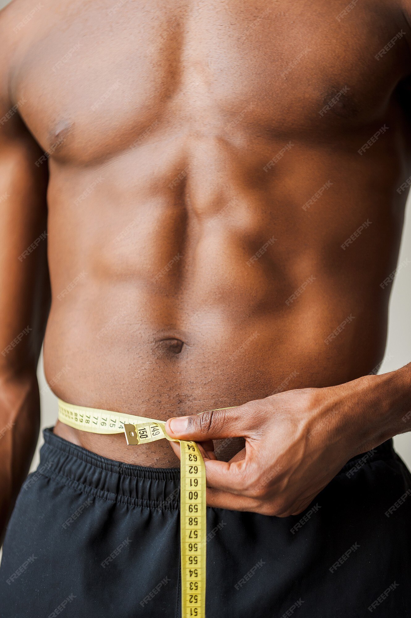 Always in good shape. Cropped image of muscular man measuring his waist  with measuring tape Stock Photo by gstockstudio