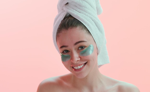 Always take care of your skin Studio portrait of a young woman smiling with an eye treatment on her face against a pink background