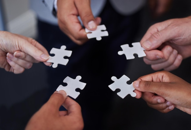 Always welcome help thats offered Shot of a group of businesspeople putting together puzzle pieces