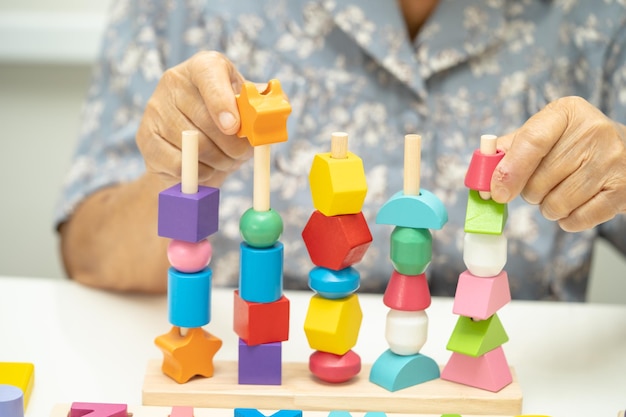 Photo alzheimer disease ad asian elderly woman patient suffering from dementia learn practical motor skills rehabilitation