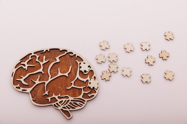 Alzheimers disease and mental health concept brain and wooden puzzle on a pink background