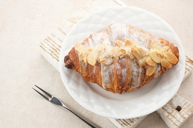 Foto amandelcroissant met besprenkelde glazuur op een wit bord