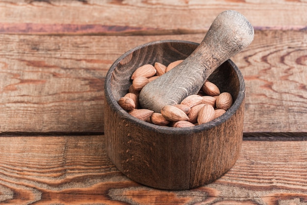 Amandelen in een vijzel met een stamper op een houten achtergrond