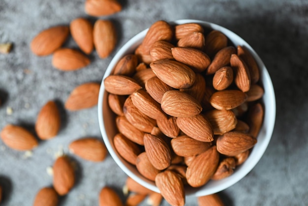 Amandelen noten bovenaanzicht op witte kom heerlijke zoete amandelen op tafel donkere achtergrond geroosterde amandelnoot voor gezonde voeding en snack