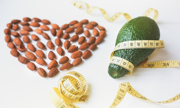 Amandelhart en avocado met meetlint Gewichtsverlies dieet Liefdevolle gezonde levensstijl Veganistisch concept Juiste voeding Sportvoeding Noten en vitamines