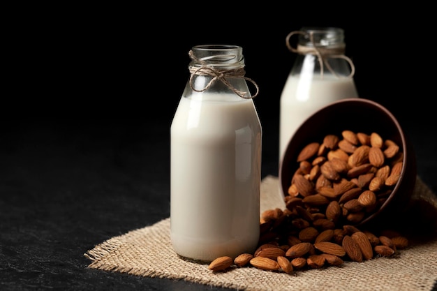 Amandelmelk in flessen met noten op donkere tafel een verscheidenheid aan zuivelproducten