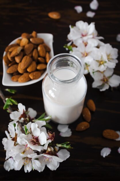 Foto amandelmelk met amandelen en amandelbloesems op tafel het veganistische alternatief voor traditionele melk