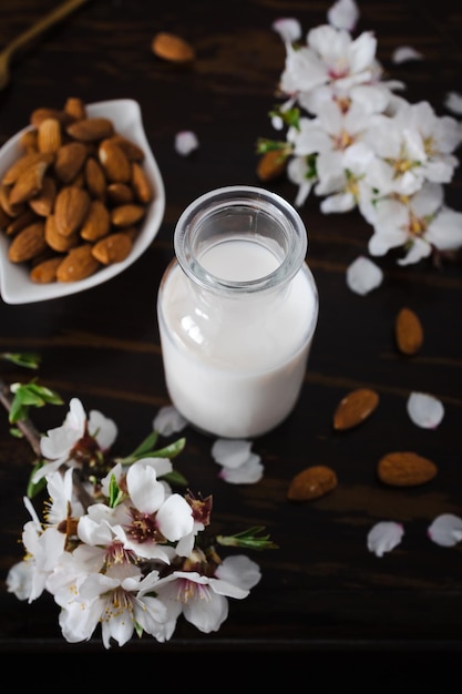 Foto amandelmelk met amandelen en amandelbloesems op tafel het veganistische alternatief voor traditionele melk