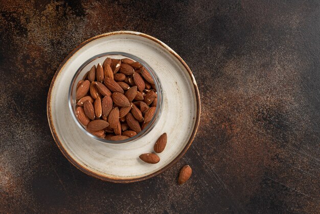 Amandelnoten in een glaskruik op een donkere geweven muur. ingrediënt voor koken