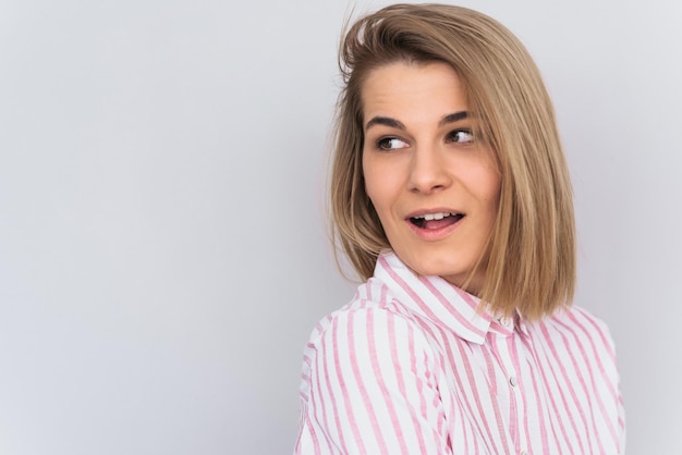 Foto stupito attraente giovane donna caucasica bionda con la pelle pulita che guarda da parte con la bocca aperta ascoltando scioccato buone notizie isolate sul muro bianco in studio concetto di emozione e stile di vita della gente