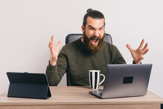 Amazed bearded man is looking at the laptop screen.