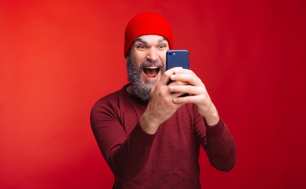 Amazed bearded man looking at smartphone, winter theme