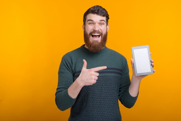 Amazed bearded man pointing at tablet screen