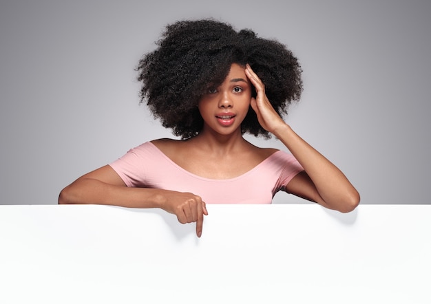 Amazed black lady showing blank poster