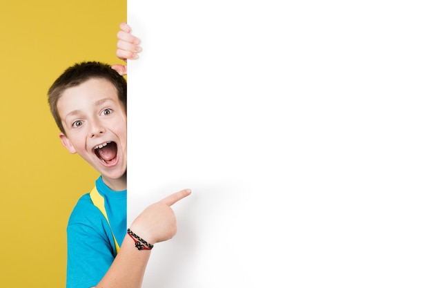 Amazed boy pointing at white billboard at side