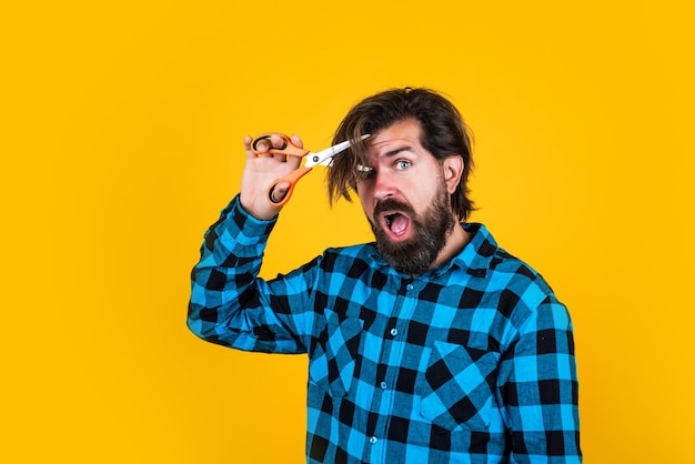 Amazed brutal male hipster cut his brunette hair with scissors barber master