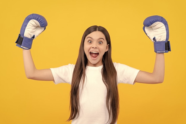 Amazed child in boxing gloves on yellow background