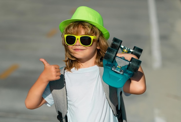 Amazed child with thumb up street portrait little kid boy years old hold skateboard posing on street