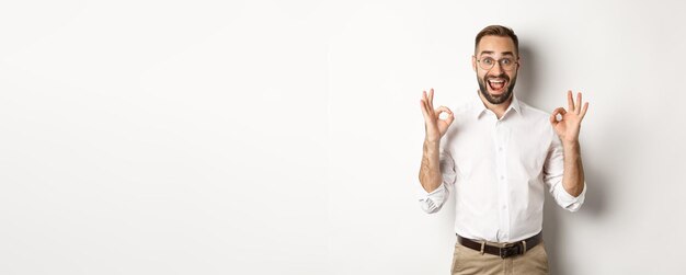 amazed entrepreneur showing okay sign and looking happy satisfied with product standing over white b