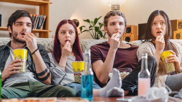 Foto amici stupiti che guardano film a casa