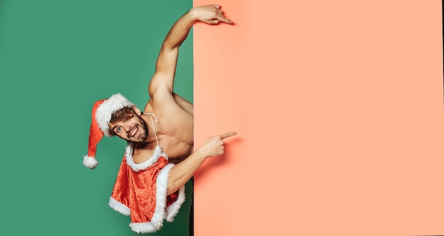 Photo amazed funny man pointing at a cardboard board sexy guy isolated over color background