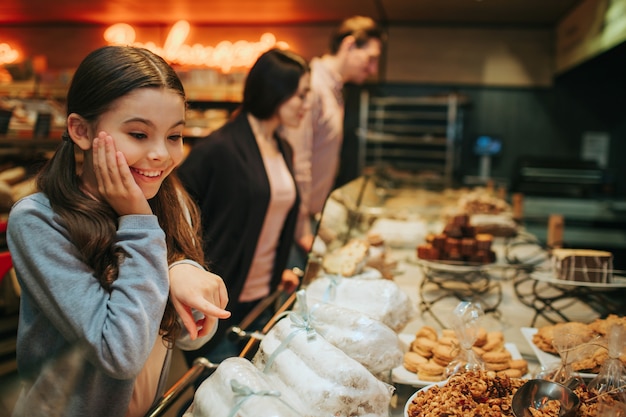 Photo amazed girl standing at shelf with candy and looking at them