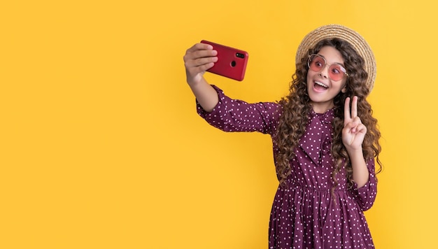 Amazed girl with curly hair taking selfie on phone