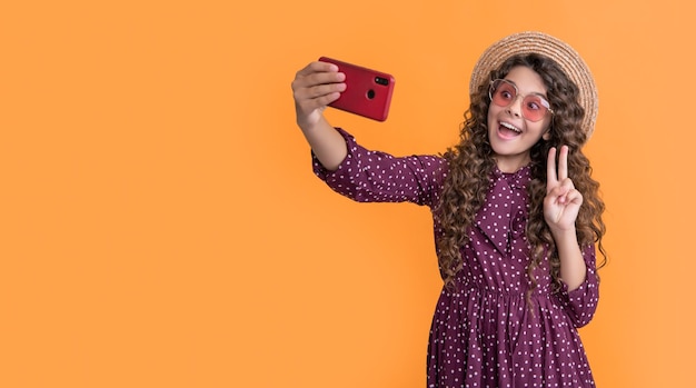 Amazed girl with curly hair taking selfie on phone