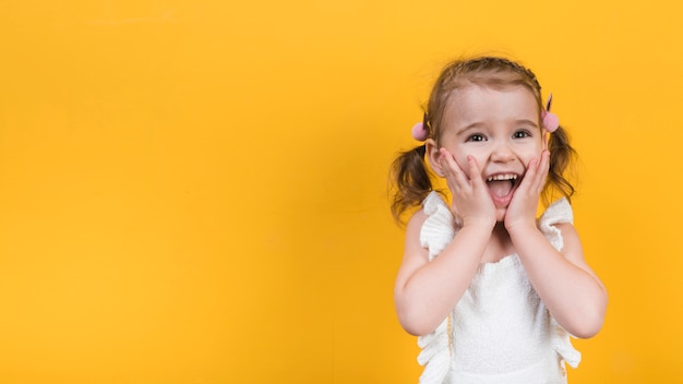 Amazed girl on yellow background 