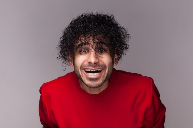 Amazed happy positive man with curly hair looking at camera laughing sees at his funny hairstyle