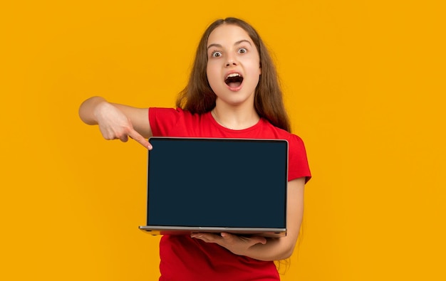 Amazed kid with laptop on yellow background