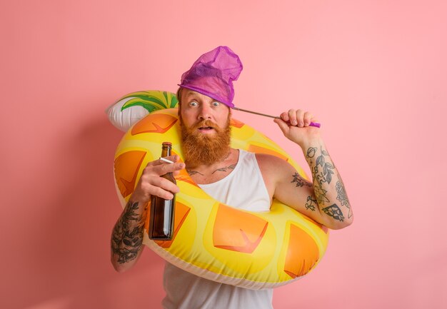 Amazed man is ready to swim with a donut lifesaver with beer and cigarette in hand