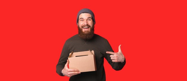 Изумленный мужчина, указывая на картонную коробку в студии