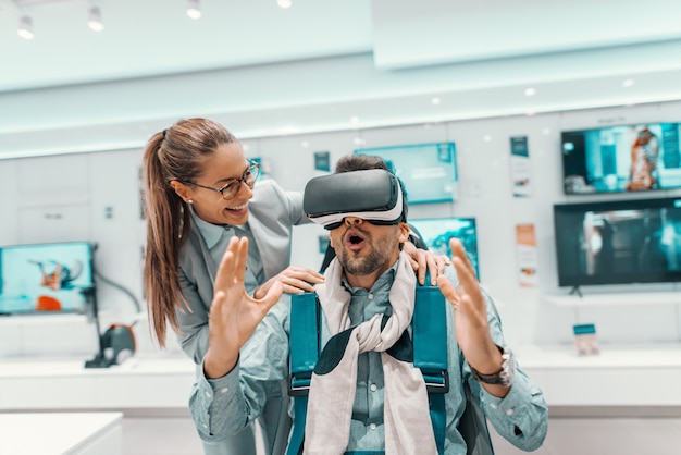 Amazed man sitting in chair and trying out vr technology next to a woman