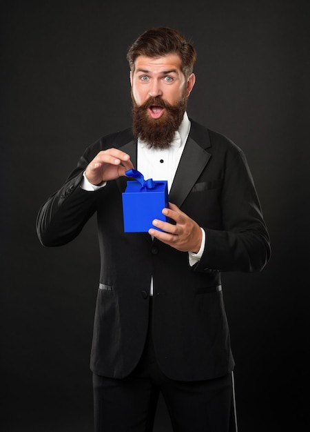 Amazed man in tuxedo bow tie formalwear on black background open box shopping sale