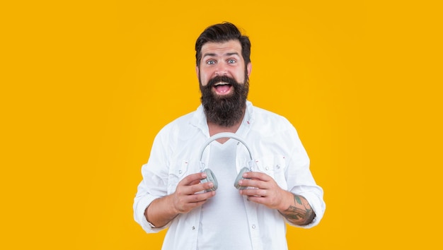 Amazed man with headphones for listening ebook studio shot of hipster holding headphones