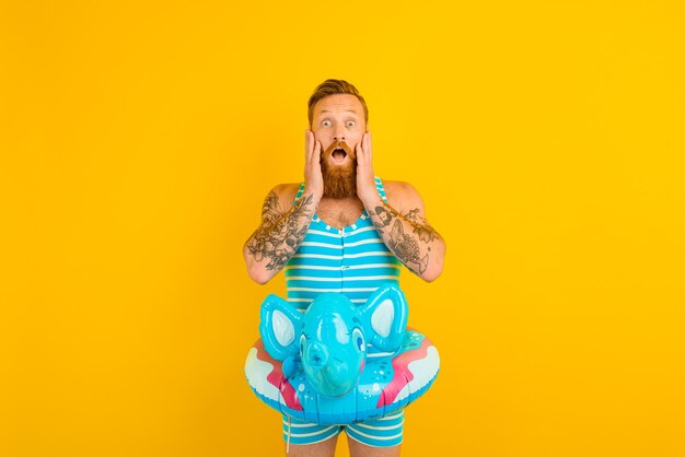 Amazed man with inflatable donut with elephant is ready to swim