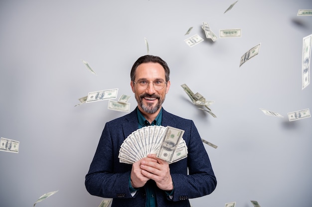 Amazed mature businessman showing money   with flying bucks